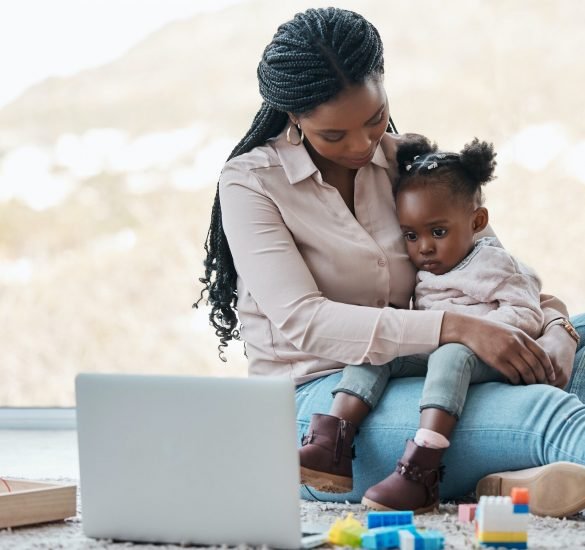 Shot of a little girl watching something on a laptop while sitting on her mothers lap